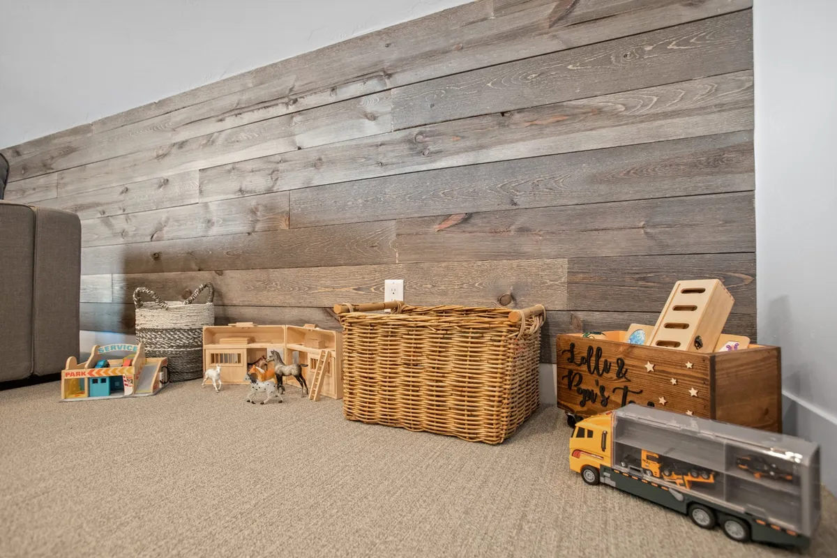 A playful corner with baskets of toys, a wooden wall, and thoughtful decor. The area is clearly designed for imaginative play, family bonding, and child-friendly amenities.