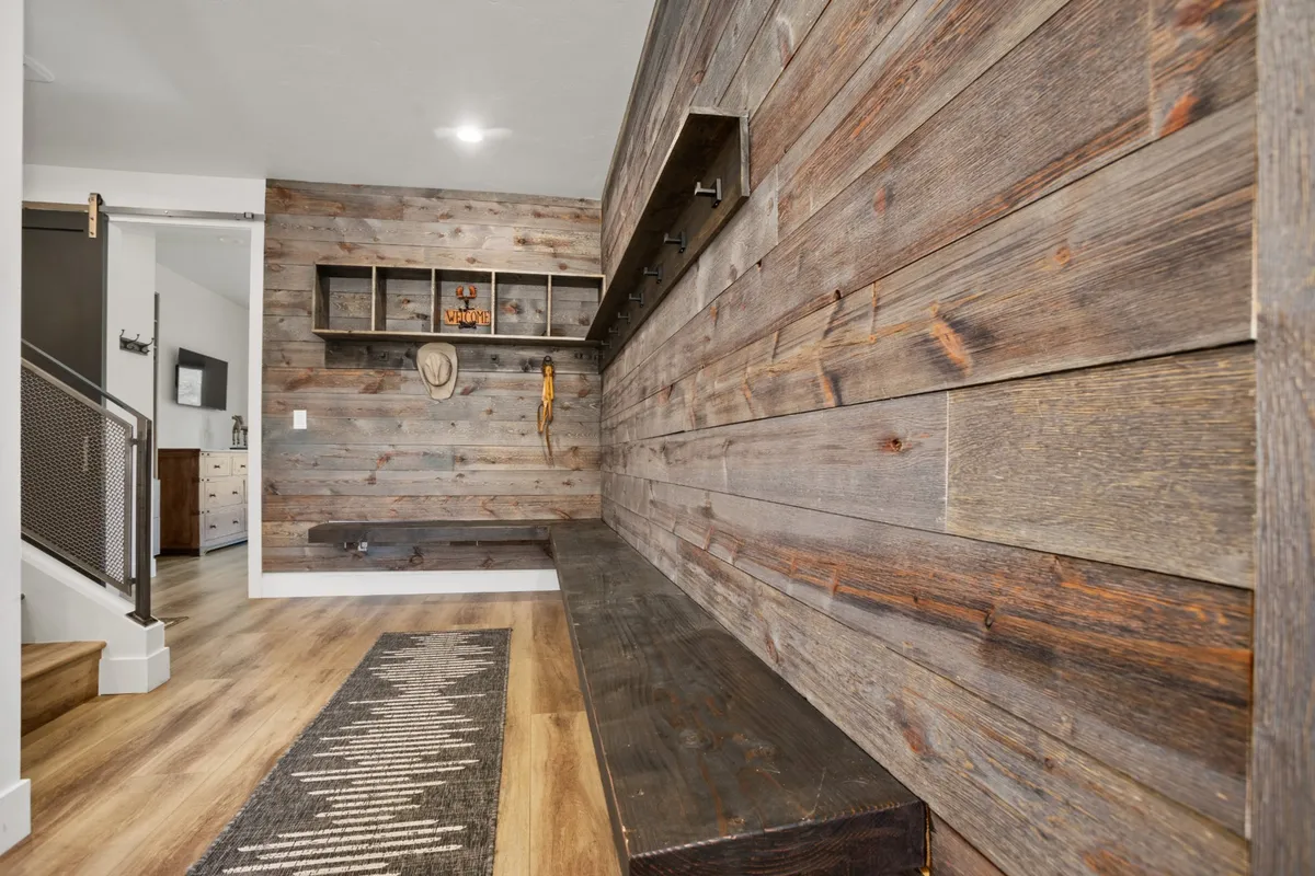 A welcoming entryway featuring a wooden wall, a comfortable sitting bench, and shelves adorned with decor, creating a warm and inviting ambiance as guests step into the home.