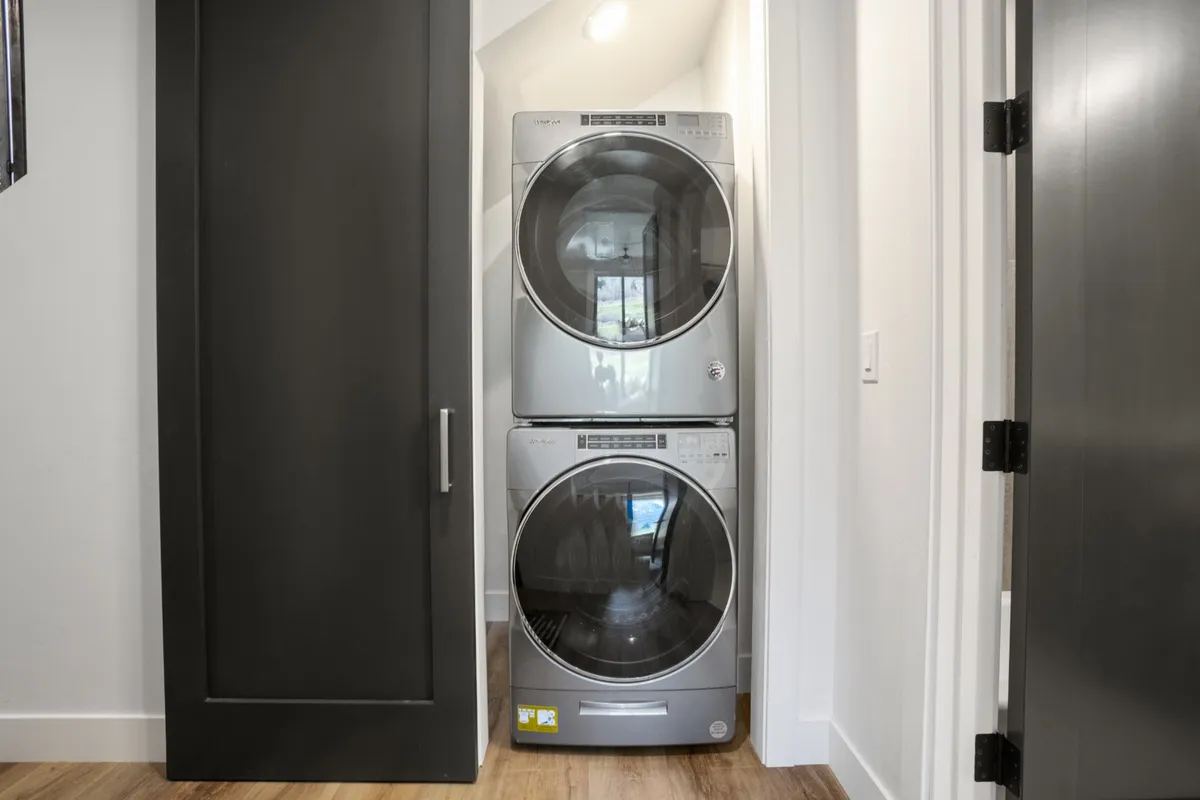 A sleek, practical laundry area with a stacked washer and dryer behind a sliding door. The space is designed for efficiency and everyday convenience, supporting a clean and organized lifestyle.