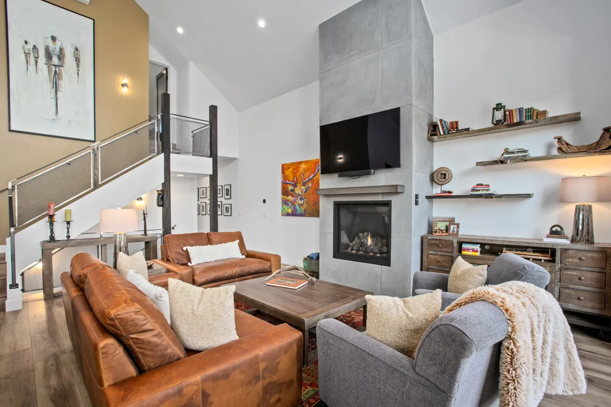 A spacious living area with a large modern fireplace, comfortable seating, sophisticated artwork, and built-in bookshelves, perfect for relaxing or entertaining guests after a day of adventure.
